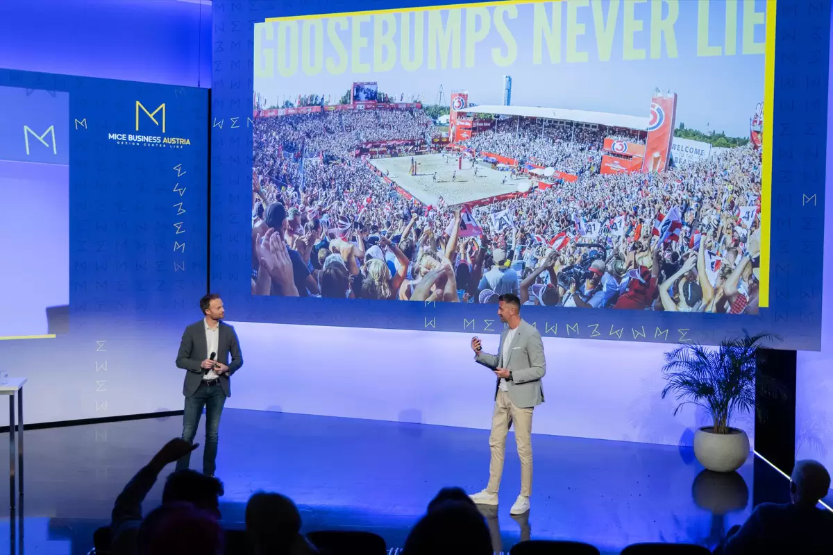 Florian Rudig und ein Gast auf einer Bühne, hinter ihnen eine Leinwand mit dem Titel Goosebumps never lie und einem vollen Stadion