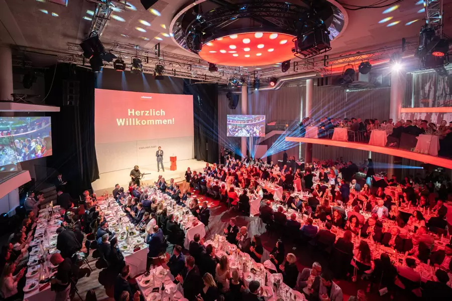 Florian Rudig auf der großen Showbühne der Wüstenrot Convention 2026 vor vollem, rot beleuchtetem Saal Florian Rudig auf der großen Showbühne der Wüstenrot Convention 2026 vor vollem, rot beleuchtetem Saal